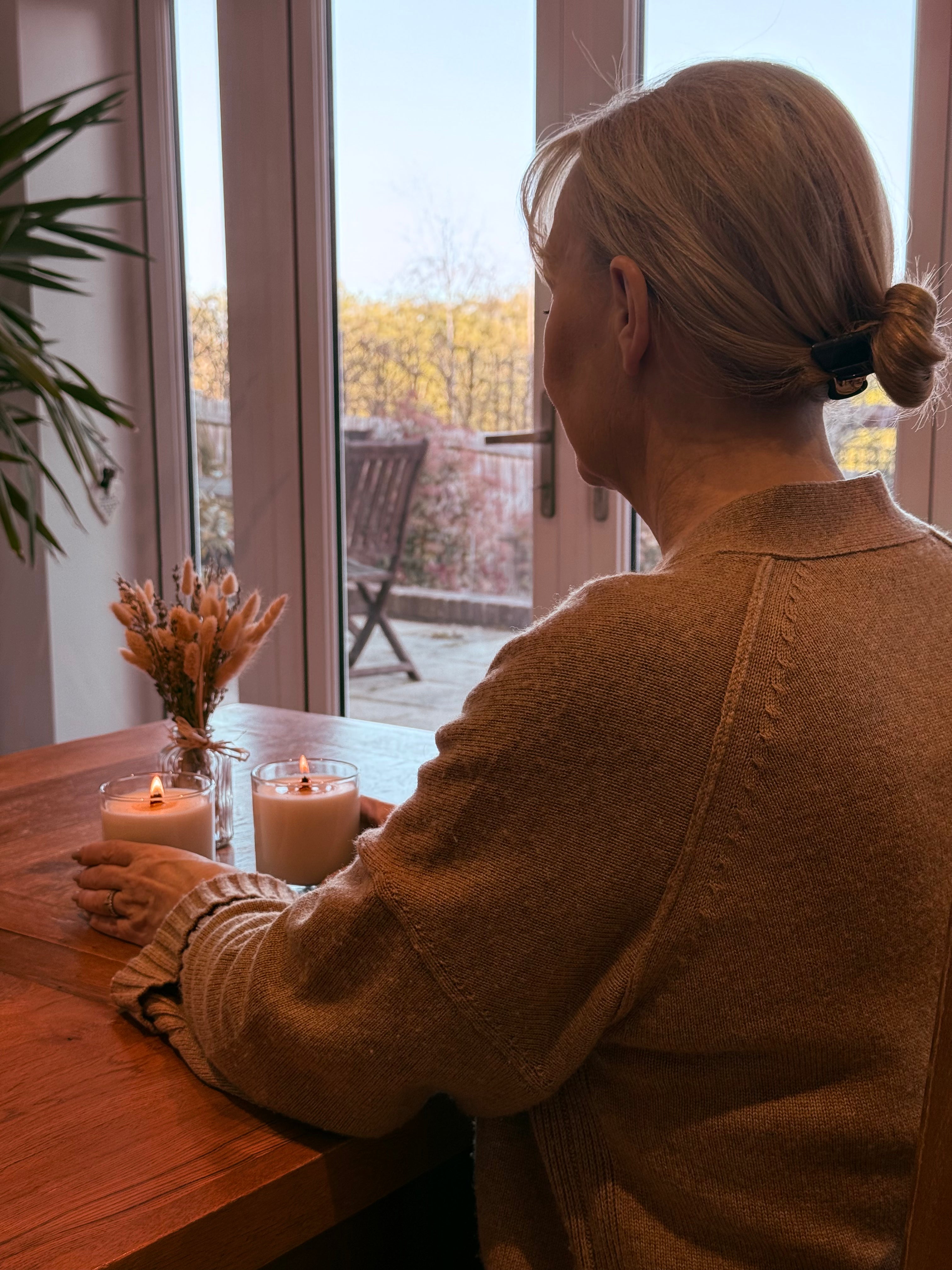 Founder of Lykke & Lumen having a calm moment with two lit candles on a wooden table