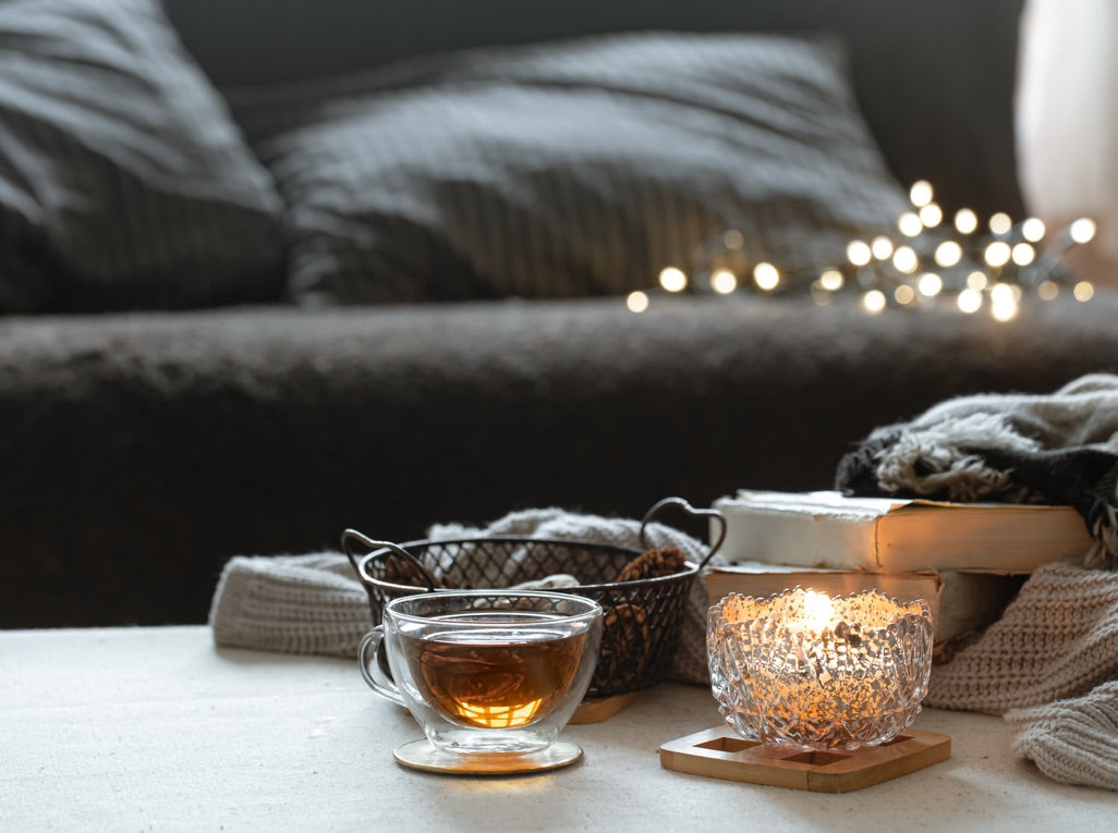 A calm nordic setting with soft furnishings, a cup of tea and a lit candle