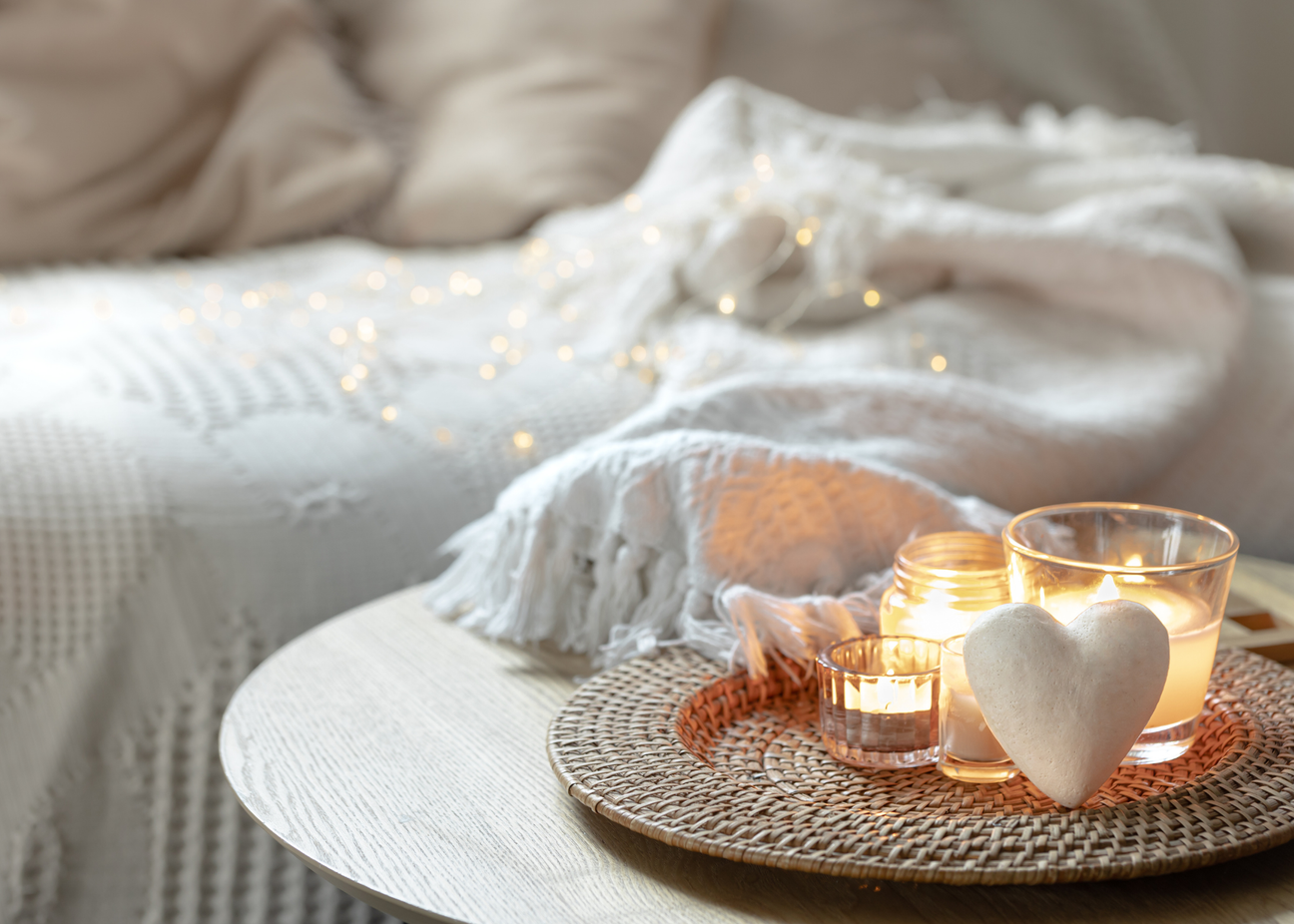 a slow mindful living setting with candle light and a ceramic white heart and fairy lights. Nordic inspired.