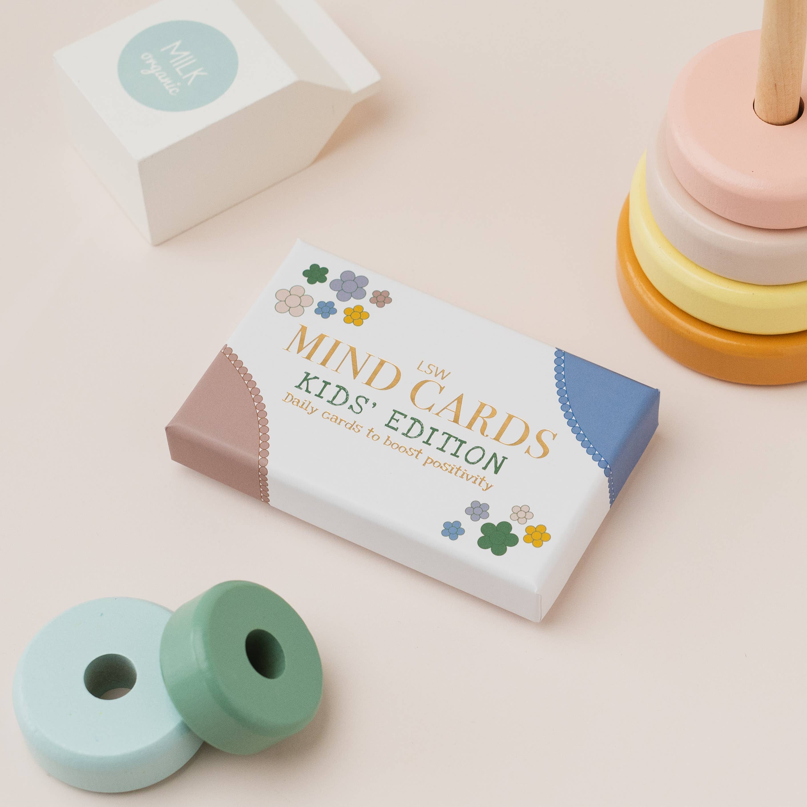 Box of 'Mind Cards Kids' Edition' on a light pink background with toys around