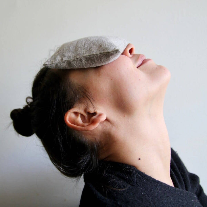 Person wearing a gray sleep mask against a plain background