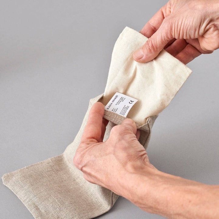 Person holding a beige fabric product with a label on a gray background