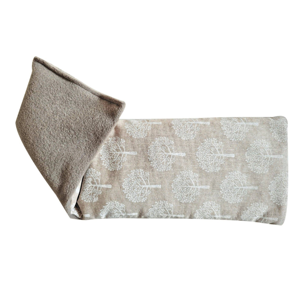 A folded fabric wheat bag made from a beige linen-like material with a repeating white tree pattern, shown on a plain white background.