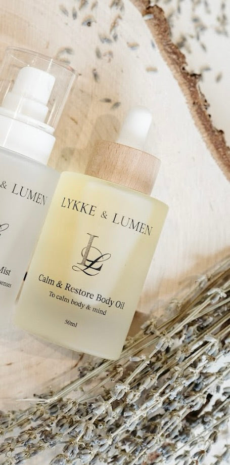Lykke & Lumen Calm & Restore Body Oil on calming background and lavender