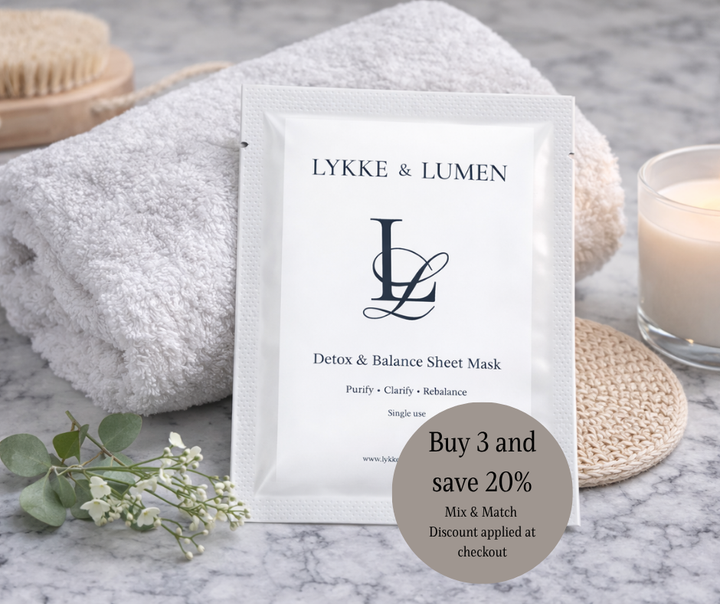 LYKKE & LUMEN detox and balance sheet mask packaging on a marble surface with towel and candle.