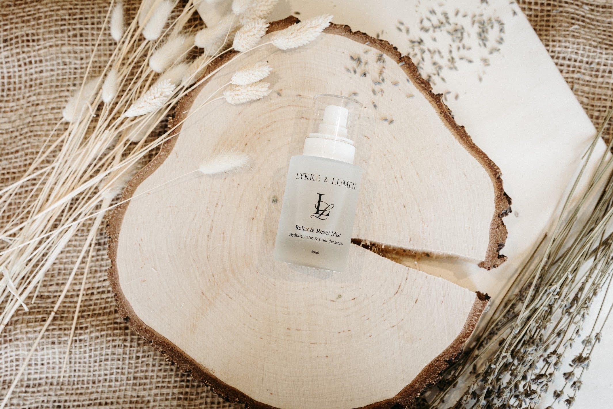 Lykke & Lumen Relax & Reset Mist arranged with dried lavender in a soft wellness-inspired setting.