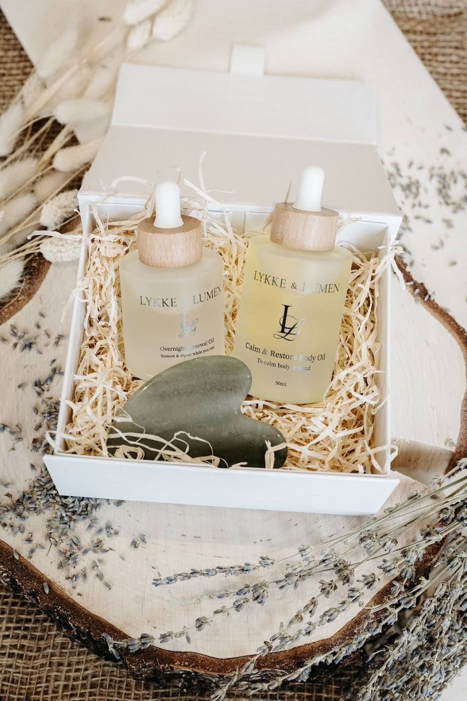 Lykke & Lumen Ritual of Restoration | Skincare & Gua Sha Set. White magnetic gift box with natural shredded wood base and containing 3 products: Overnight Renewal Oil, Calm & Restore Body Oil and a gua sha facial massage tool