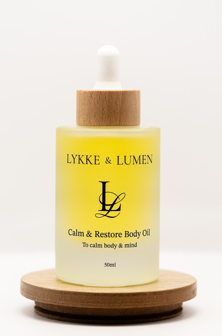 Lykke & Lumen Calm & Restore Body Oil standing on wooden plinth and white background