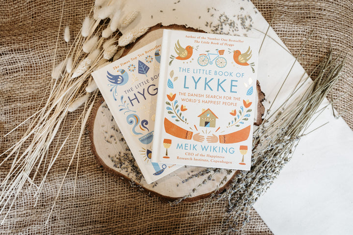 Two books titled 'The Little Book of Lykke' and 'The Little Book of Hygge' on a wooden surface with dried plants.