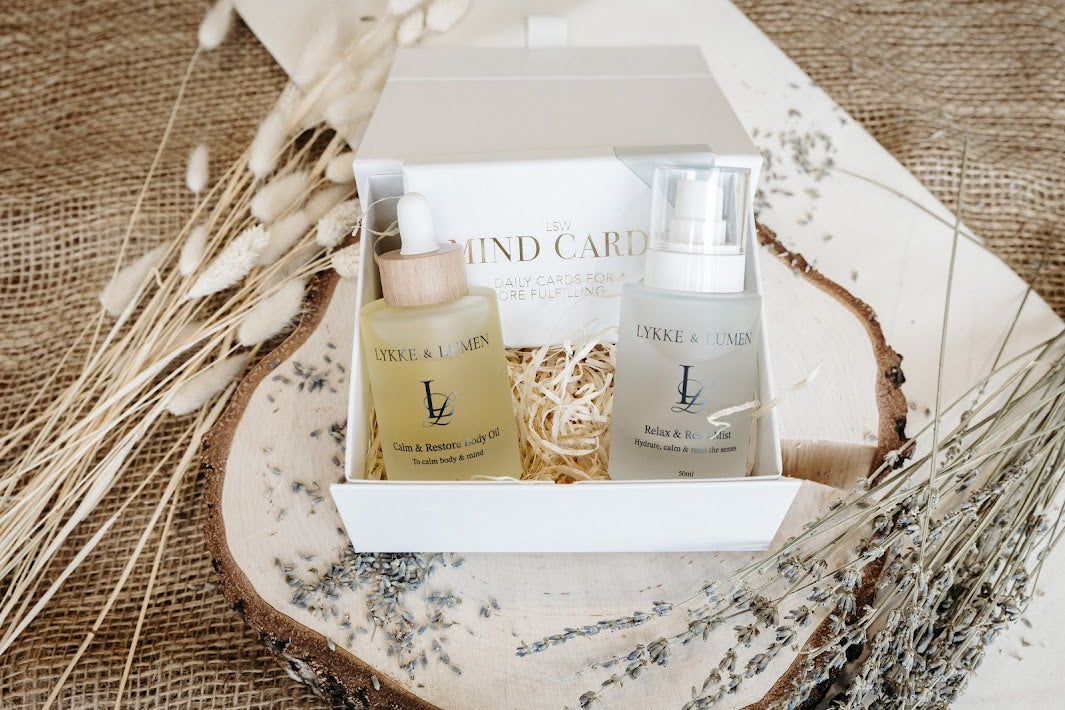 Lykke & Lumen wellness gift set featuring Calm & Restore Body Oil, Relax & Reset Mist and mindfulness cards presented in a luxury white gift box with dried lavender styling.