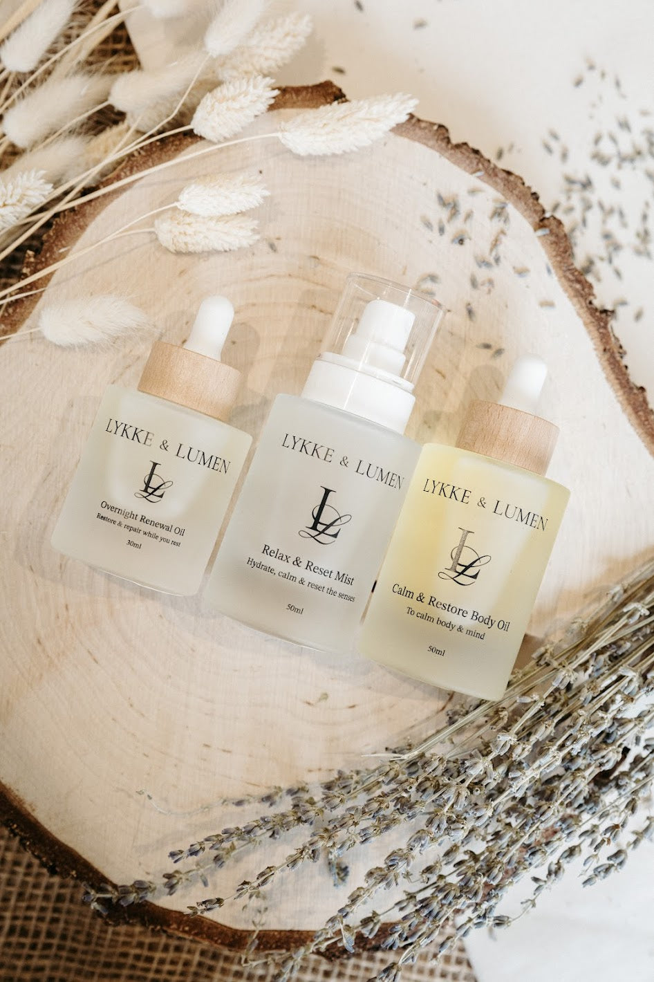 Lykke & Lumen skincare ritual collection featuring Overnight Renewal Oil, Relax & Reset Mist and Calm & Restore Body Oil styled with dried lavender in a calming wellness setting.