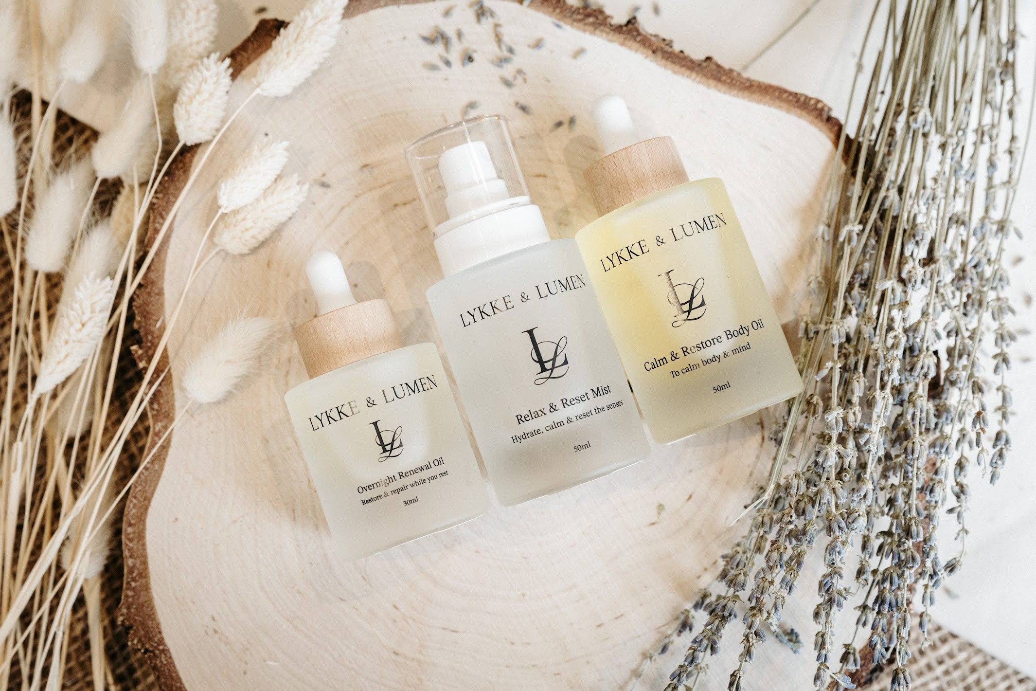 Lykke & Lumen skincare ritual collection featuring Overnight Renewal Oil, Relax & Reset Mist and Calm & Restore Body Oil styled with dried lavender in a calming wellness setting.