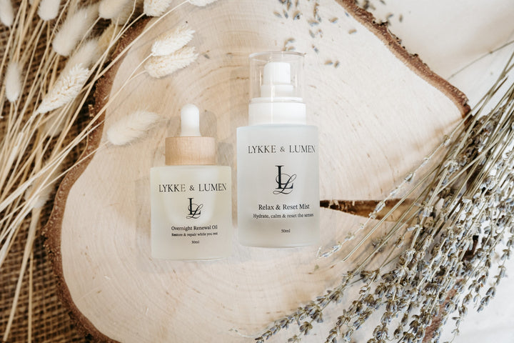 Lykke & Lumen skincare ritual collection featuring Overnight Renewal Oil, and Relax & Reset Mist styled with dried lavender in a calming wellness setting.