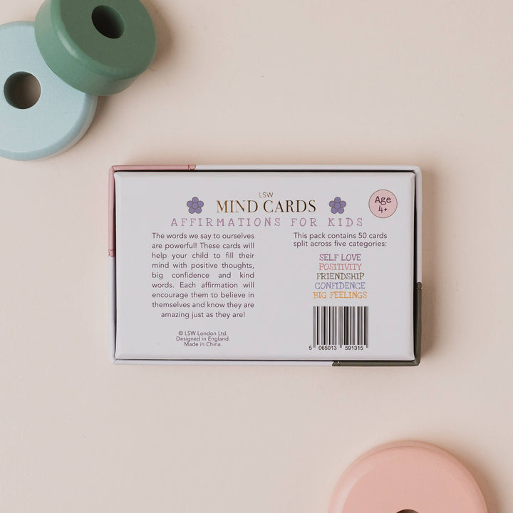 Box of 'Mind Cards Affirmations for Kids' on a light pink background with pastel-colored objects.