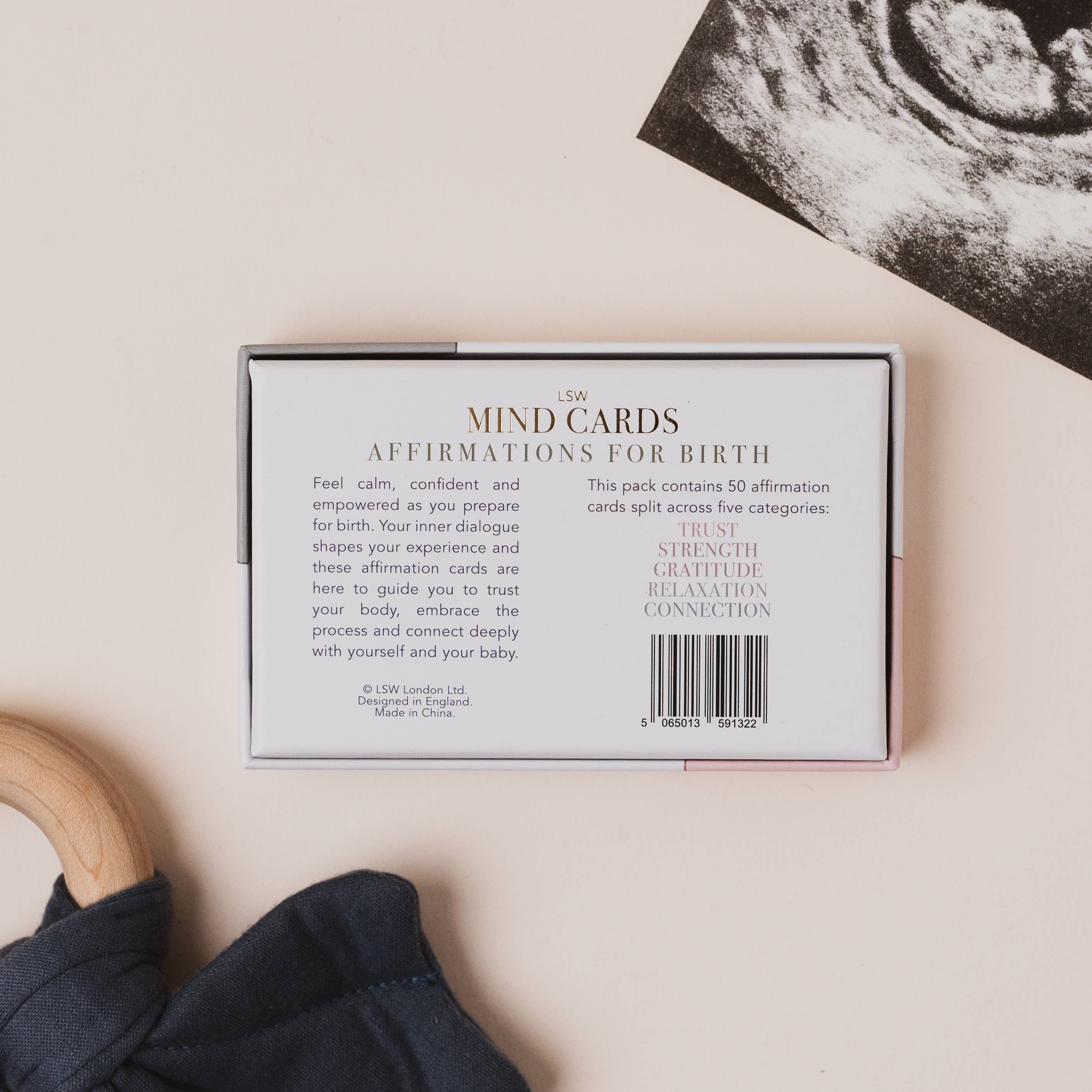 Box of 'MIND CARDS Affirmations for Birth' on a neutral background with a baby item and ultrasound photo.