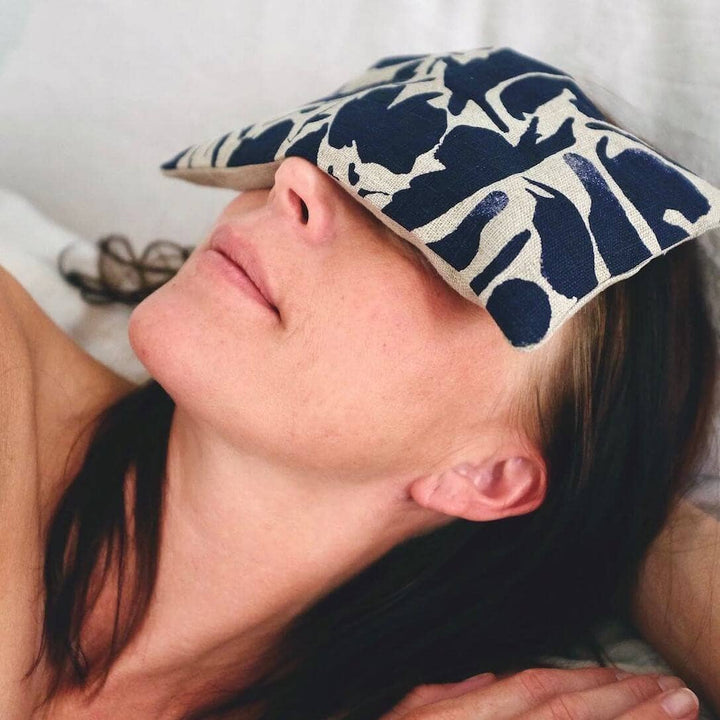 Person lying down with a floral-patterned eye mask on their forehead